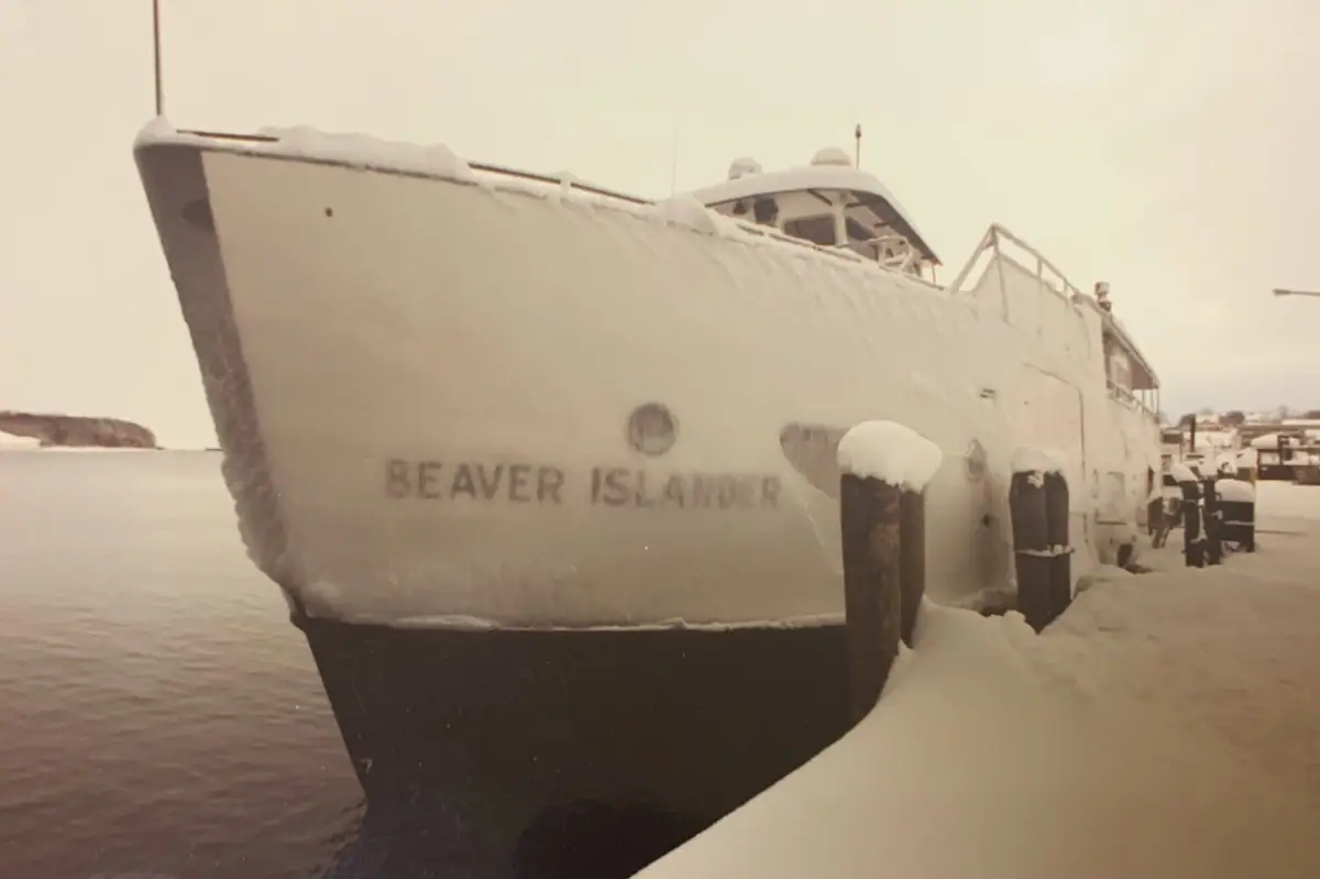 A snow- and ice-covered ferry is moored beside a snowy dock in winter.