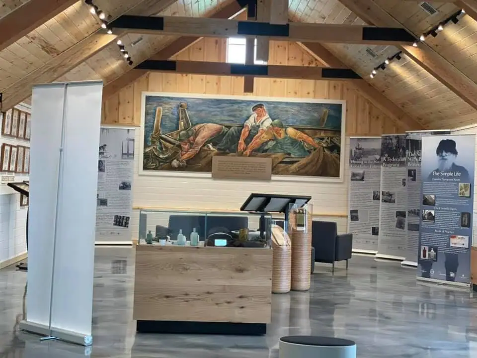 Interior exhibition space with a maritime painting, display cases, and interpretive panels.
