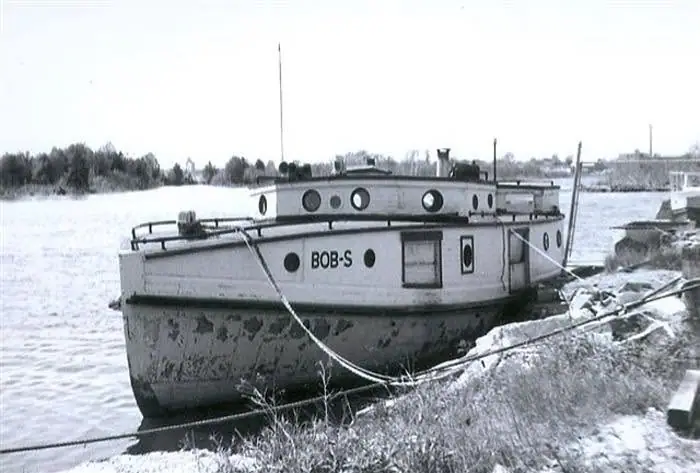 A small fishing tug marked “BOB-S” sits beside a snowy shoreline.