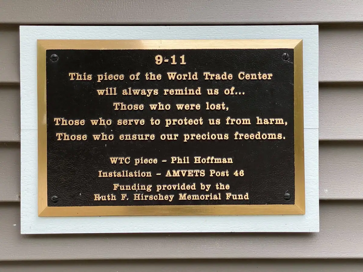 A commemorative plaque with gold lettering mounted on an exterior wall.
