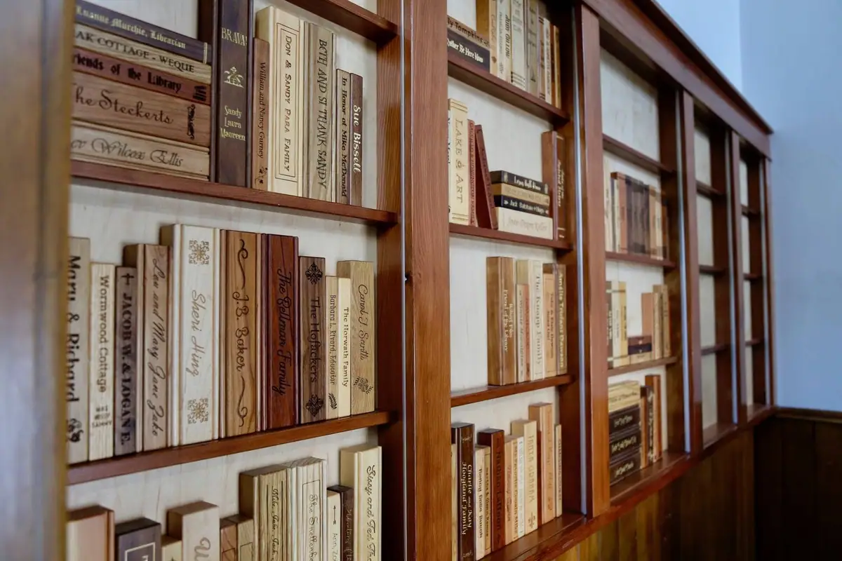 Wooden bookcases display books and engraved book spines bearing donor names and dedications.