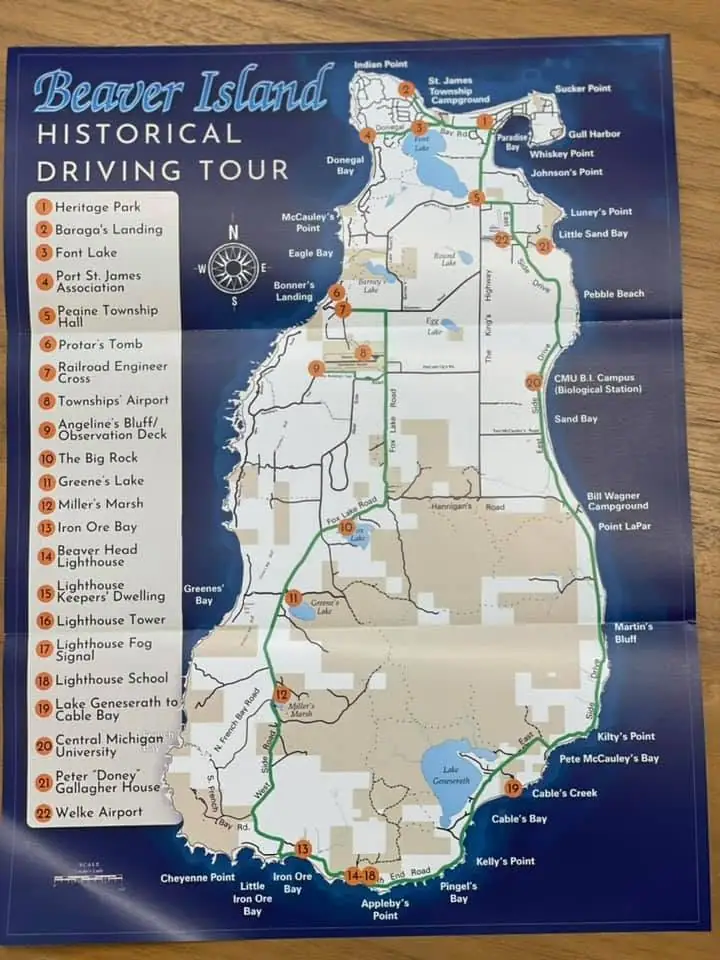 Photograph of a printed historical driving-tour map with numbered attractions, roads, shoreline, and a compass rose.