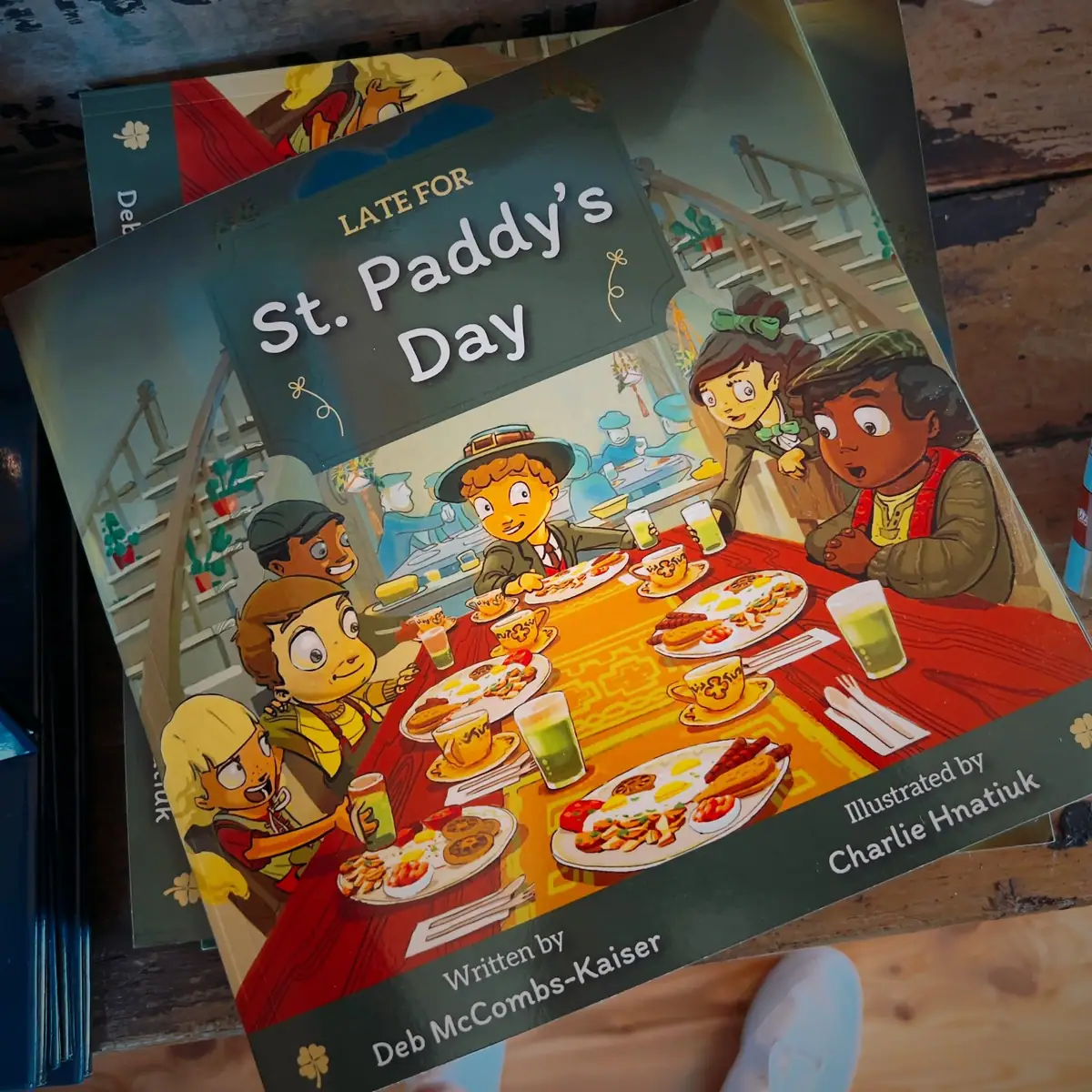 Photograph of an illustrated book cover showing children eating together at a table.