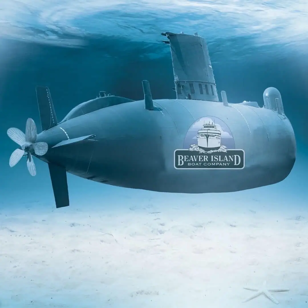 A gray submarine with a company logo appears underwater above a sandy seafloor.