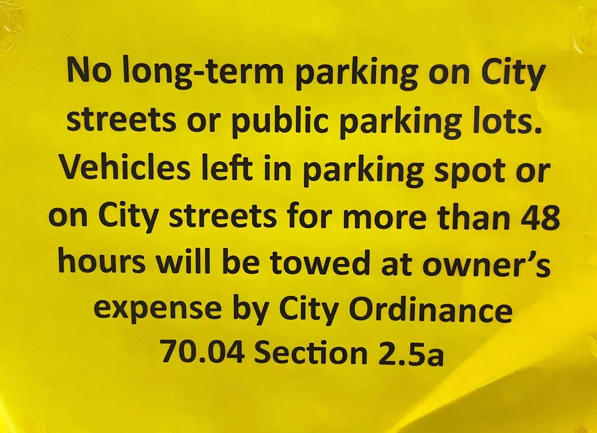 A yellow notice warns that vehicles parked more than 48 hours will be towed at the owner's expense.