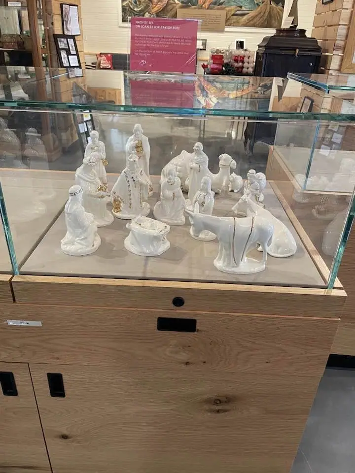 White ceramic nativity figurines displayed in a glass museum case.