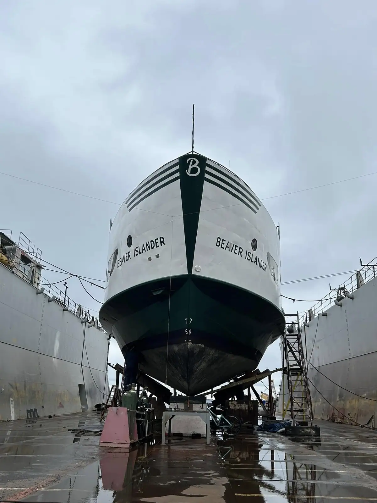 A passenger ferry rests in a wet dry dock, viewed head-on from below its painted bow.