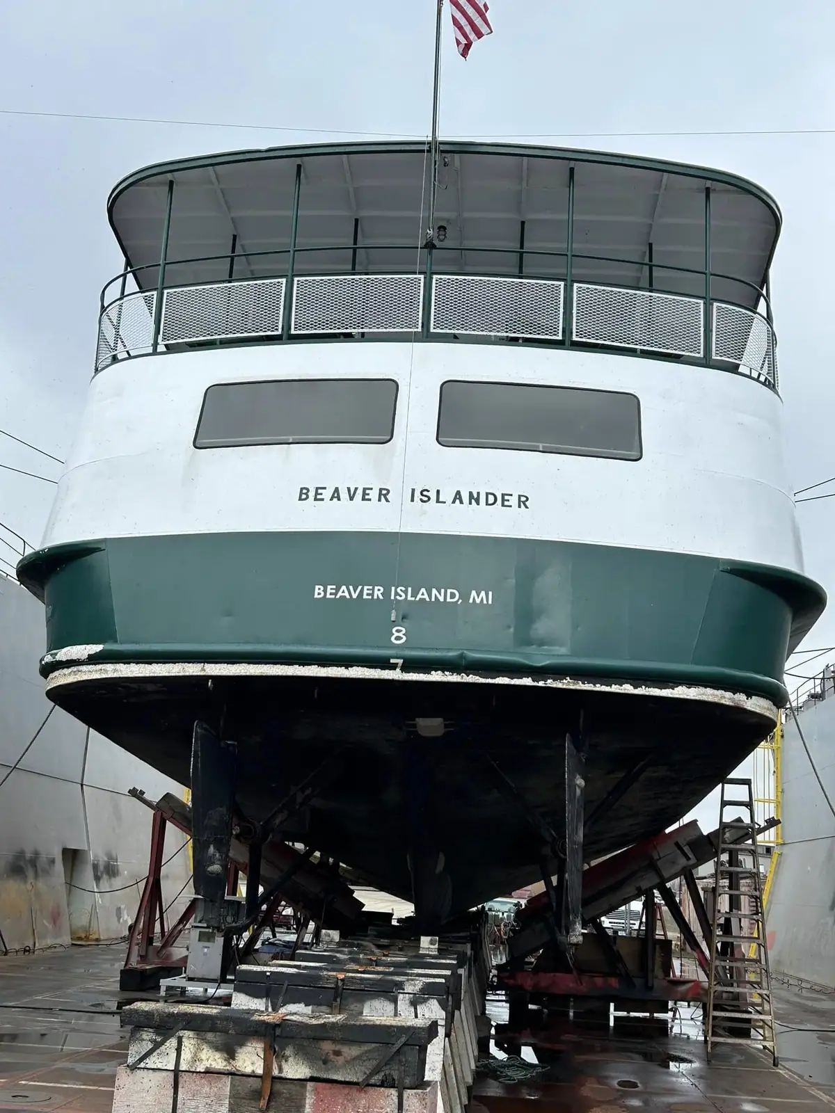 A passenger ferry named Beaver Islander rests on supports inside a boat maintenance building.