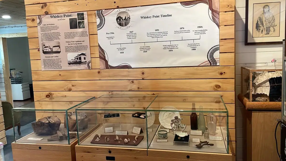 Museum exhibit with historical panels, a timeline, framed images, and glass cases of artifacts.