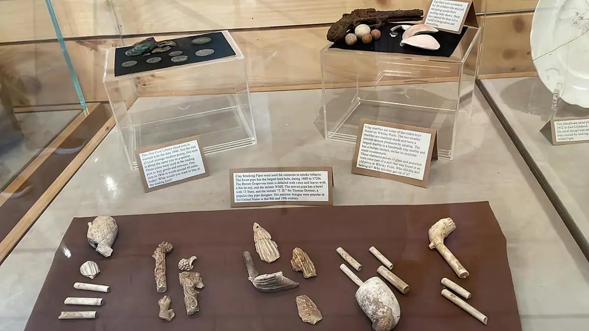 Museum display case containing coins, small artifacts, and exhibit labels.