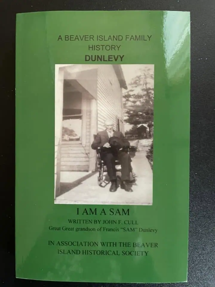 Green booklet cover with a black-and-white photograph of a seated man outside a house.