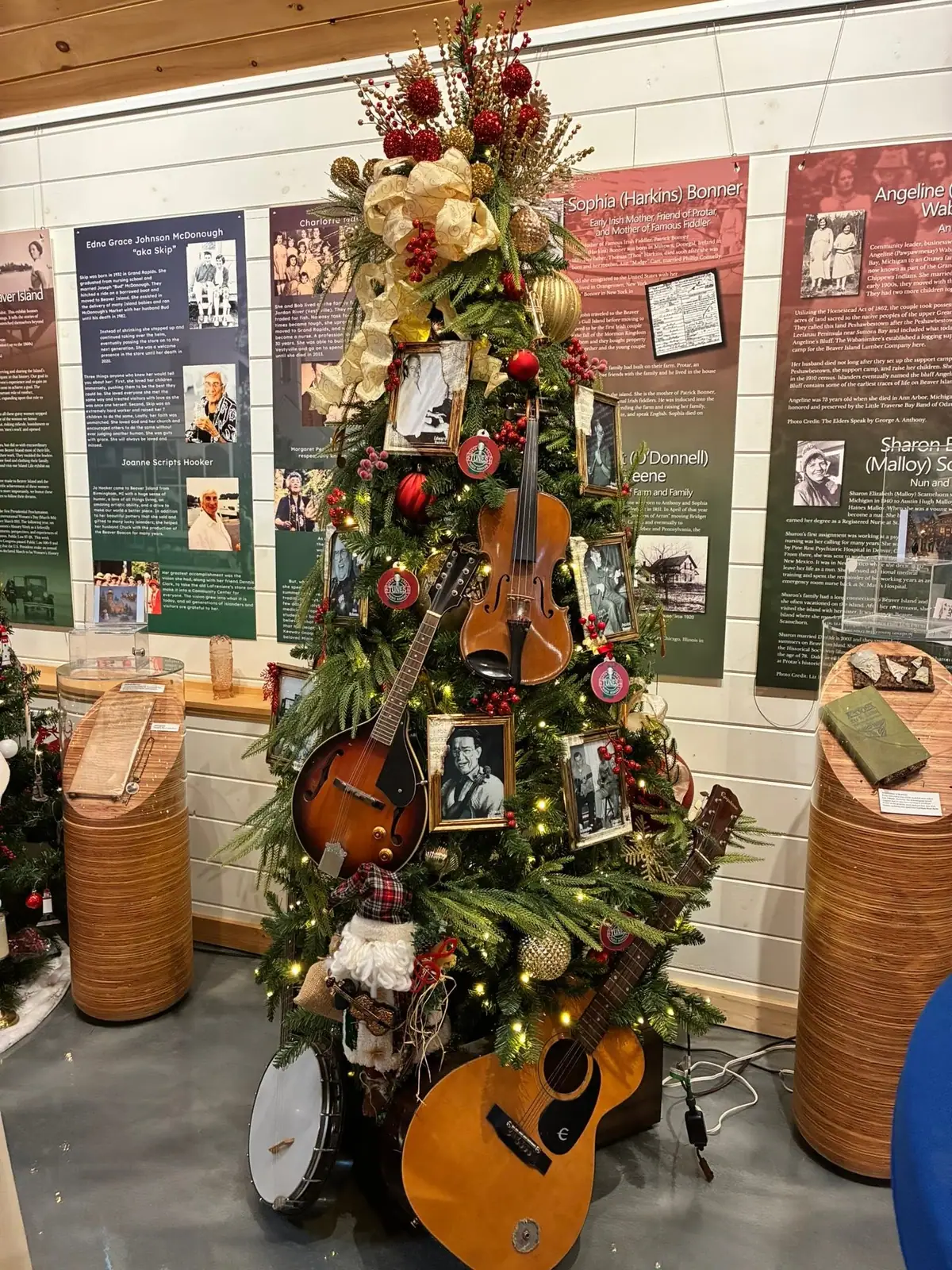 A decorated evergreen display tree covered with musical instruments, framed photographs, ornaments, and lights.
