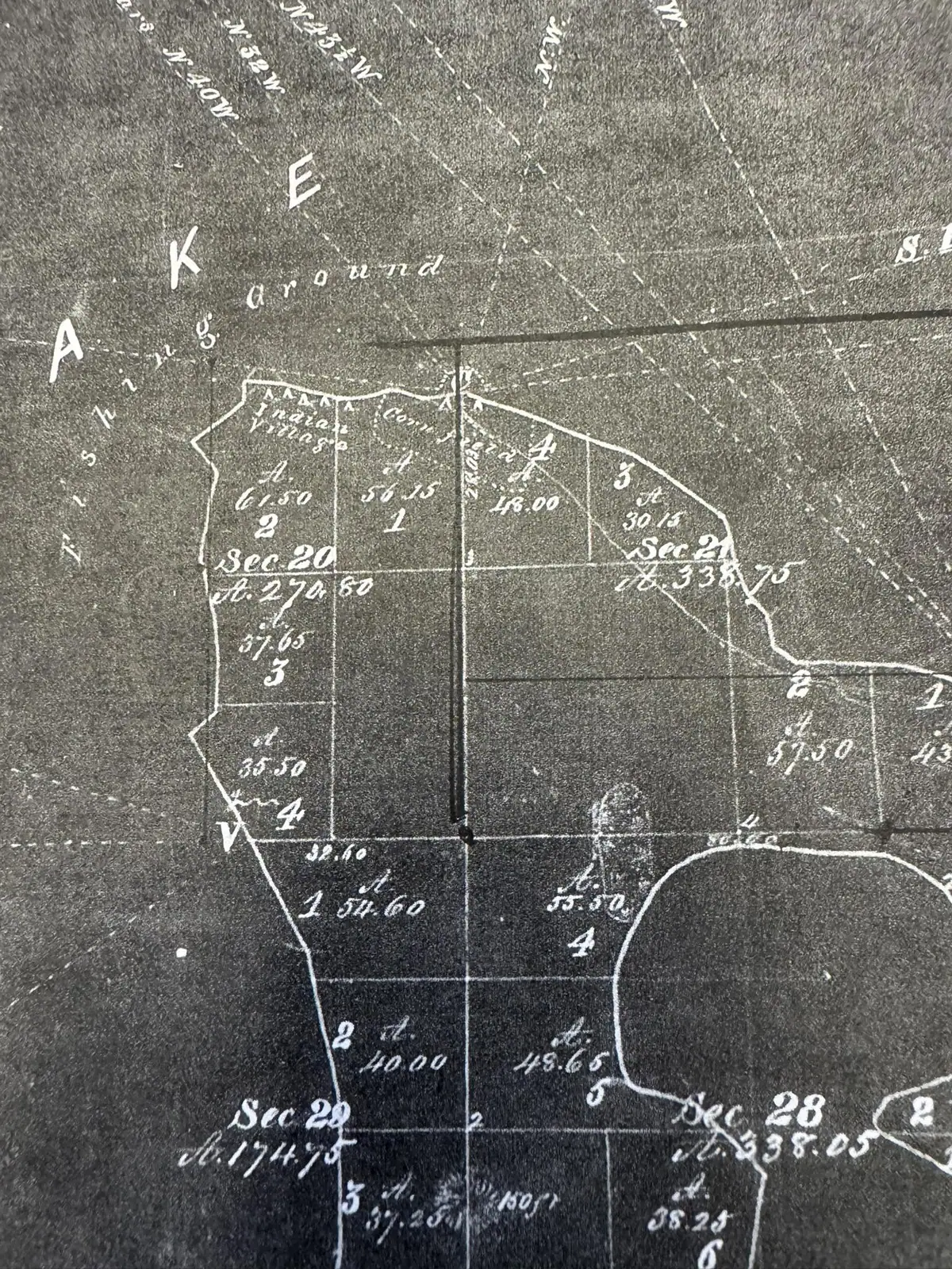 Close-up photograph of a hand-drawn survey map with section lines, property boundaries, bearings, and handwritten measurements.
