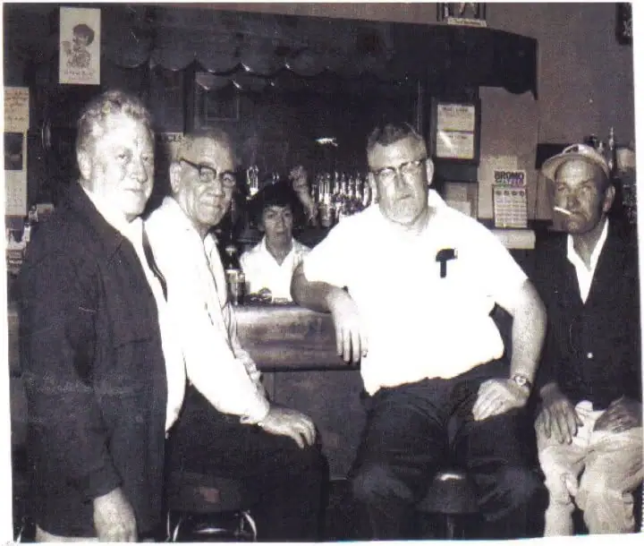 Five people pose at a counter in a black-and-white photograph.