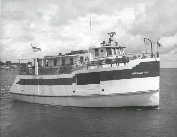 Black-and-white photograph of a ferry named Emerald Isle moving through the water near shore.