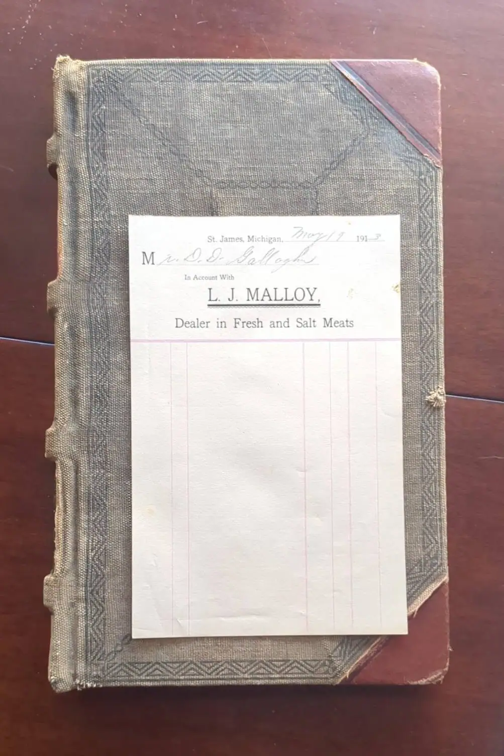 Photograph of a cloth-bound account book and business form with printed text and handwritten entries.