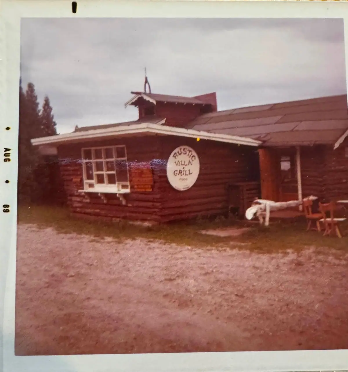 Rustic log restaurant with a circular RUSTIC VILLA GRILL sign and porch.