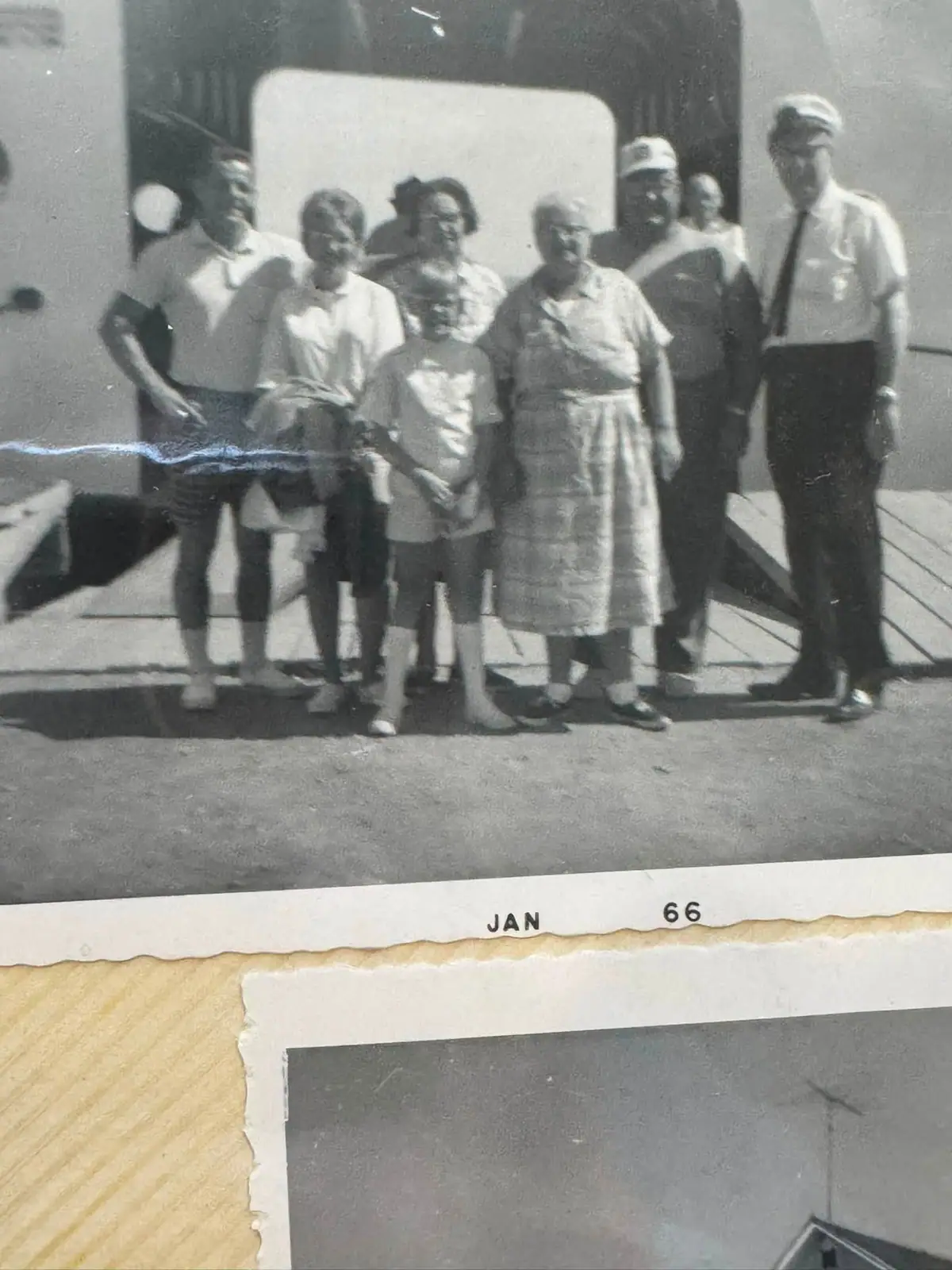 Black-and-white photograph of nine people standing together on a wooden deck, mounted on a yellow-bordered page.