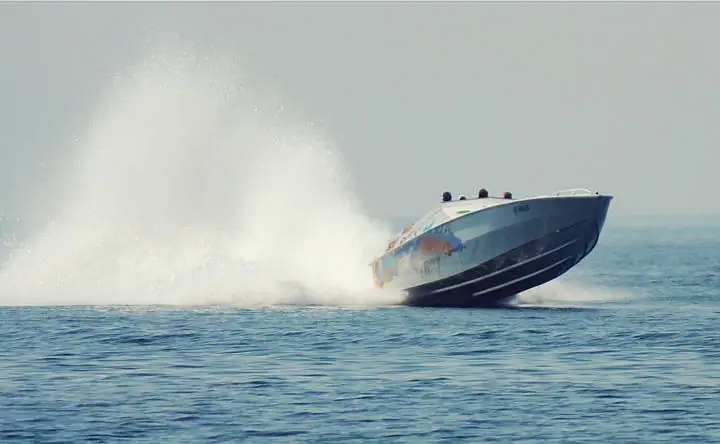 A racing motorboat speeds across open water, throwing up a broad plume of spray.