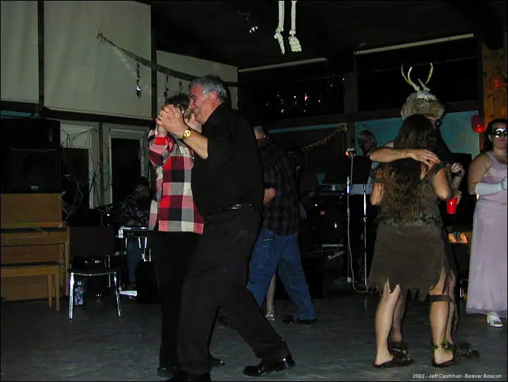 Adults dance at an indoor party, including one person wearing an antlered costume.