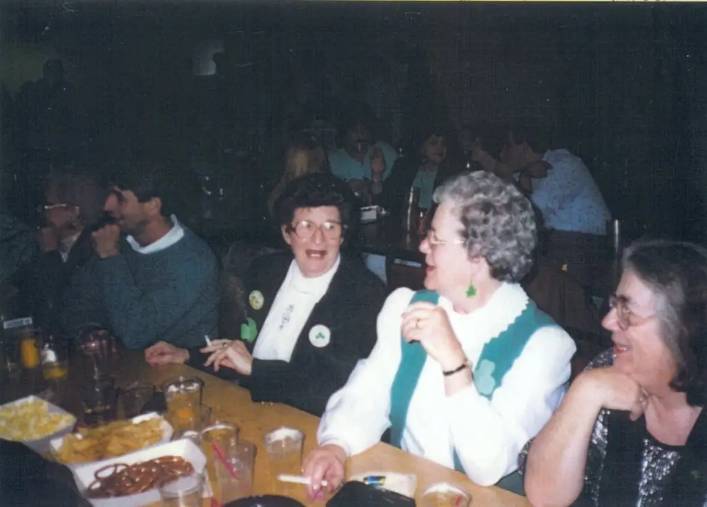 People sit around a table indoors with snacks and drinks during a social gathering.