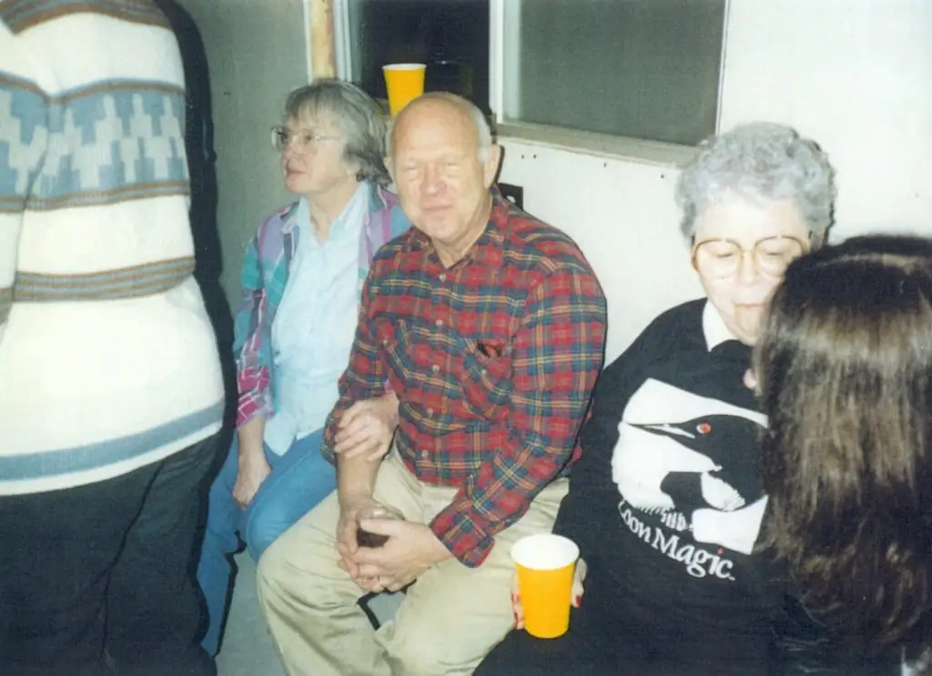 Five people sit together indoors, including a man in a plaid shirt and a person wearing a “Loon Magic” sweatshirt.