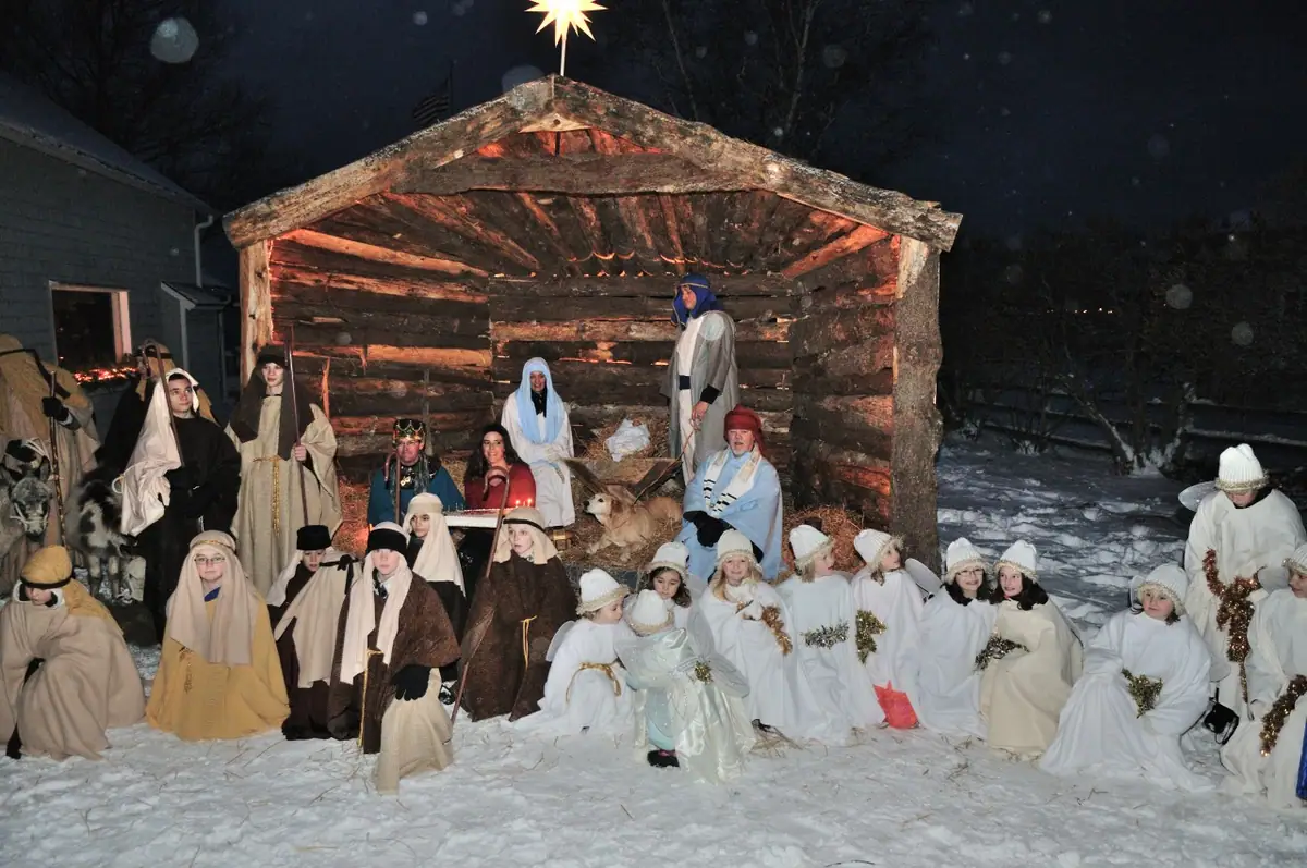 People in robes and winter clothing pose before a wooden shelter beneath a bright star in the snow.