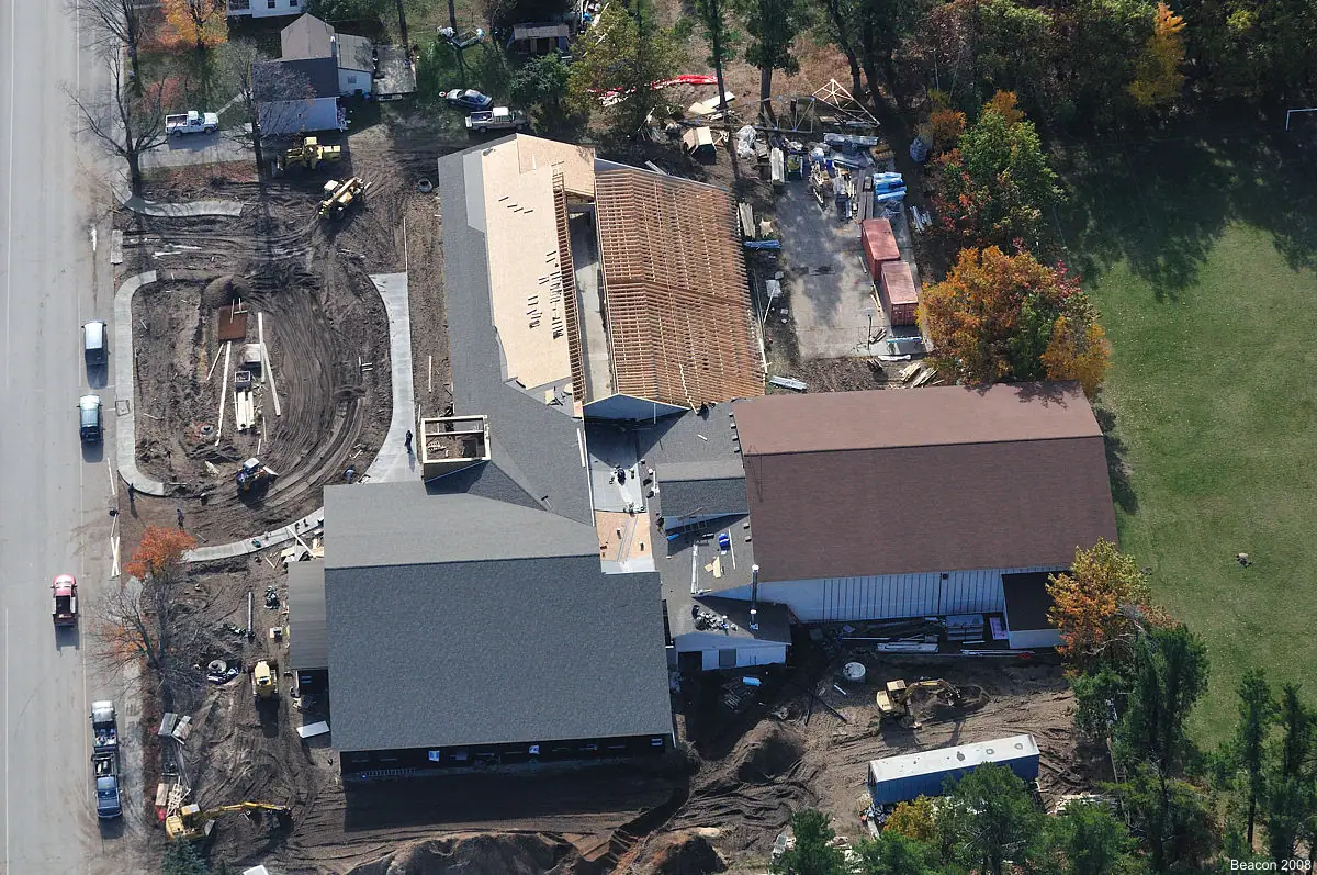Aerial photograph of a large building complex under construction beside a road, with equipment and vehicles around it.