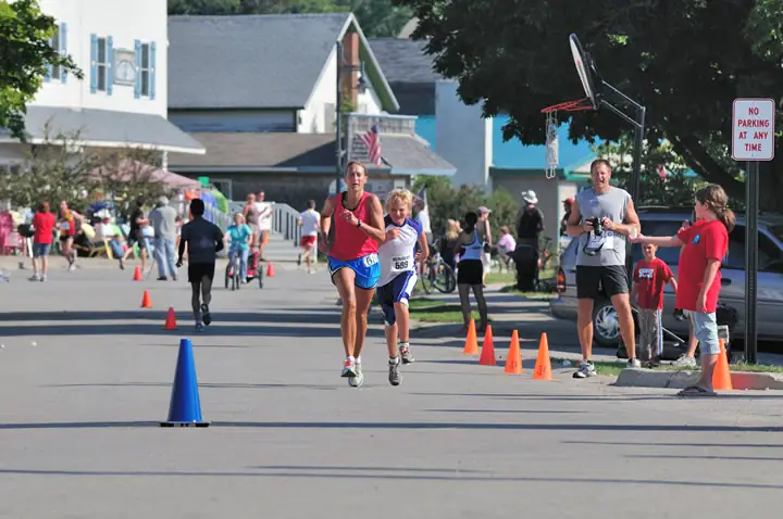 Runners move along a coned-off street while spectators watch from the sidewalk.