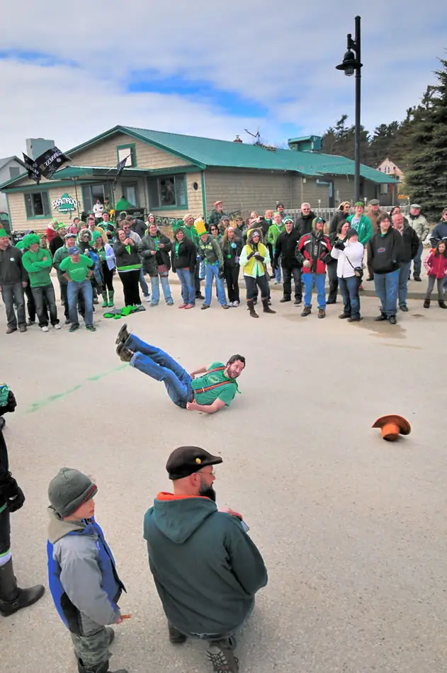 A person lies on a paved area while a crowd in green clothing watches outside a building marked “SHAMROCK.”