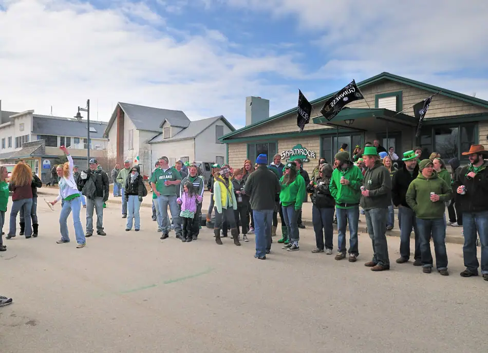 A costumed crowd gathers and dances in front of a pub during a street celebration.