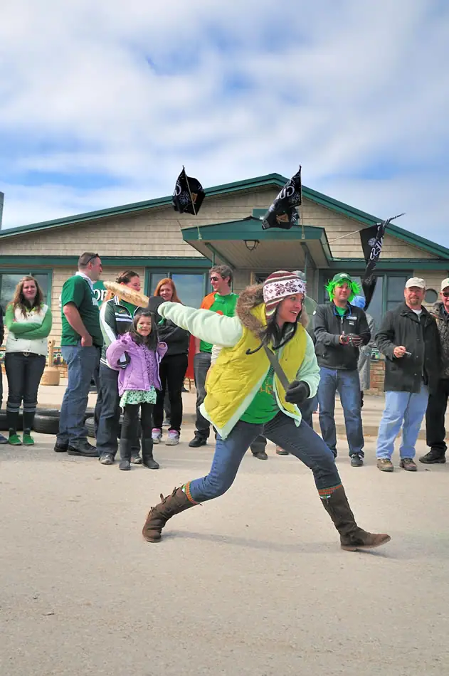 A costumed participant gestures energetically before a crowd outside a building decorated with flags.