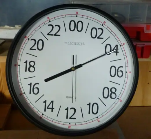 A round black-rimmed clock with a white 24-hour face and black hands, photographed indoors.