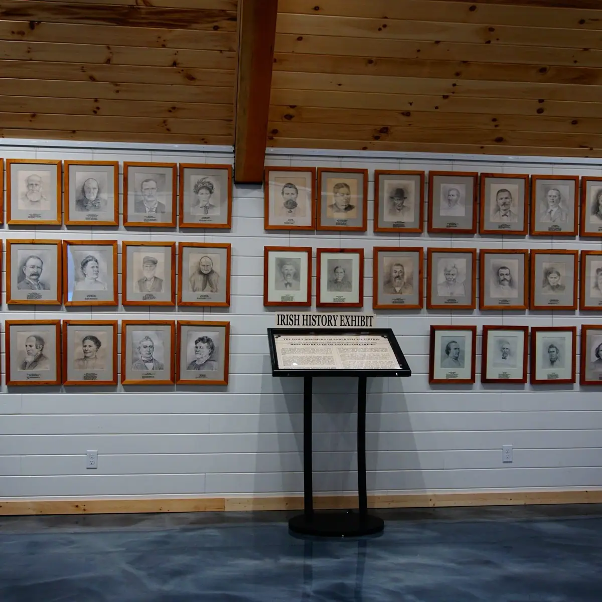 Interior exhibit wall with framed portrait drawings and an Irish history display.