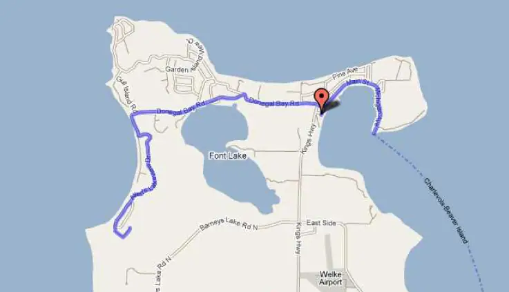 Road map showing a blue route, a red location marker, roads, water bodies, and an airport.