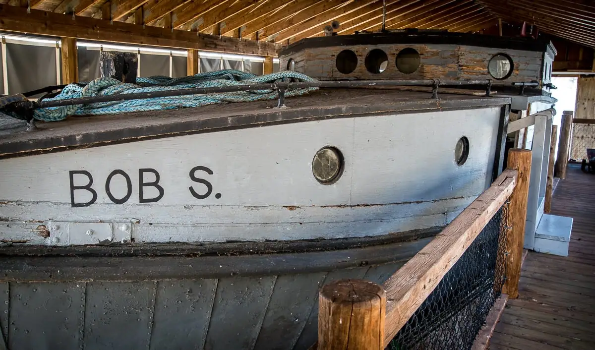 Close view of a weathered wooden boat with ropes, portholes, and the painted lettering “BOB S.”