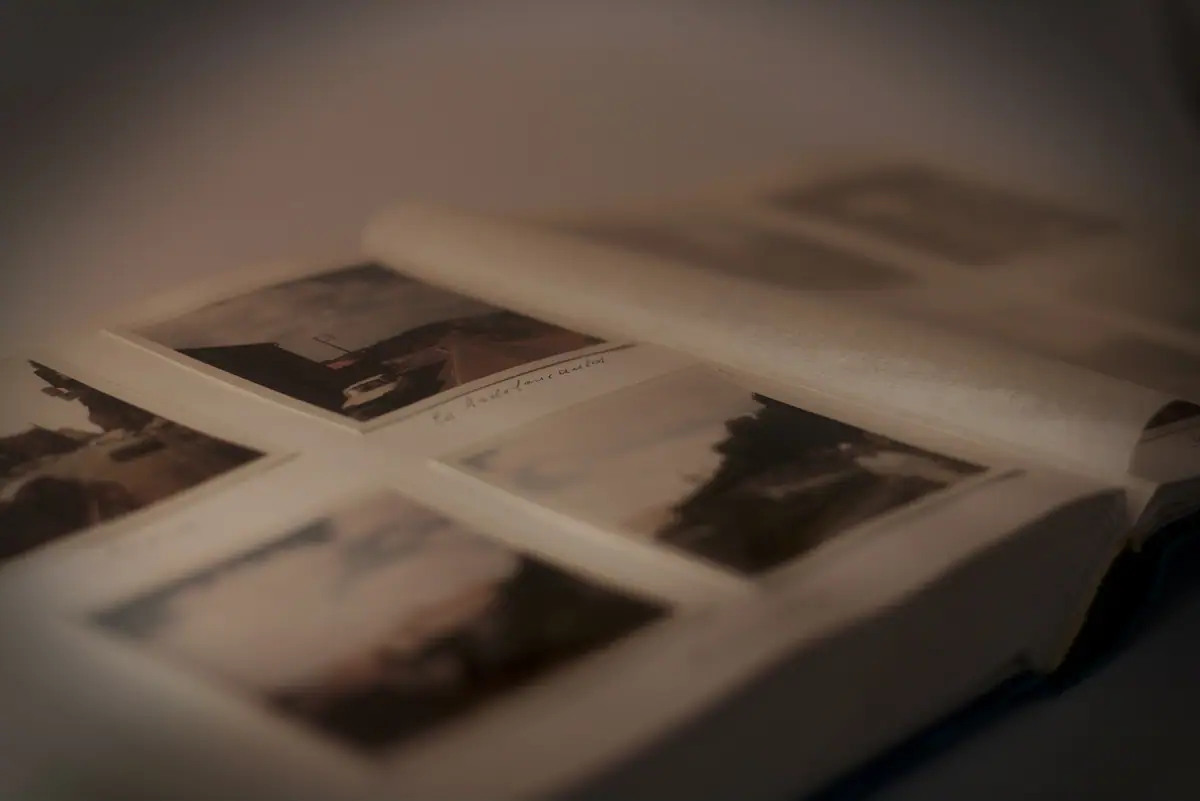 An open photo album holds several blurred photographic prints and handwritten notes.